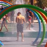 A young boy pauses after walking through a series of water hoops